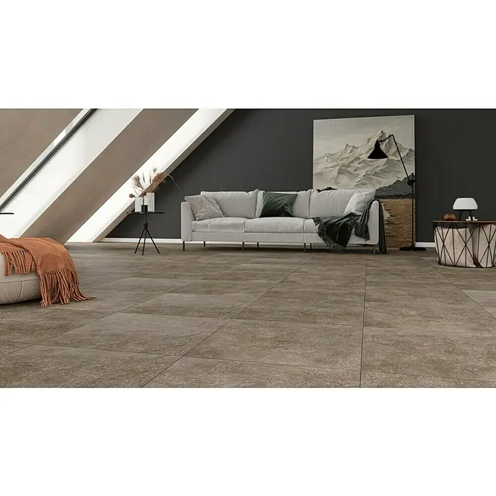 Feinsteinzeugfliese Geo Brown - 60 x 60 cm, Braun, Schimmernd - Helle Räumlichkeit mit strukturierten Bodenfliesen in Braun, ergänzt durch ein Sofa, einen Beistelltisch und eine Stehlampe für ein stilvolles Ambiente.