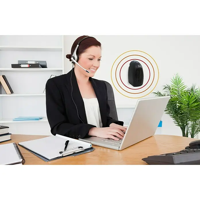 Heizlüfter Starlyf Fast Heater - 400 W, Weiß - Eine Frau mit Headset arbeitet an einem Laptop, während ein kleiner, tragbarer Heizlüfter für Wärme sorgt.