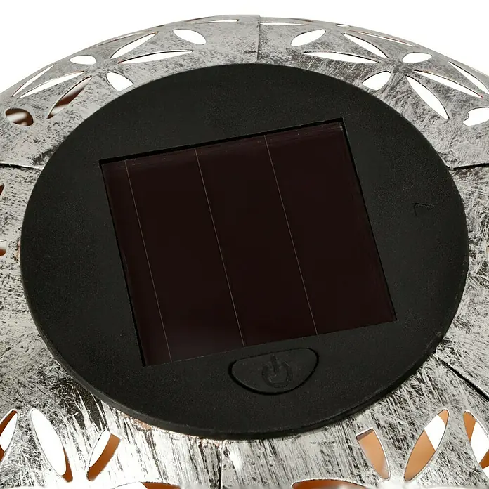 BAUHAUS Solar-Dekoleuchte Kugel - 0,06 W, Silber, IP44 - Nahaufnahme einer Solarleuchte mit Solarpanel und Ein-/Ausschalter auf einer dekorativen silbernen Oberfläche.