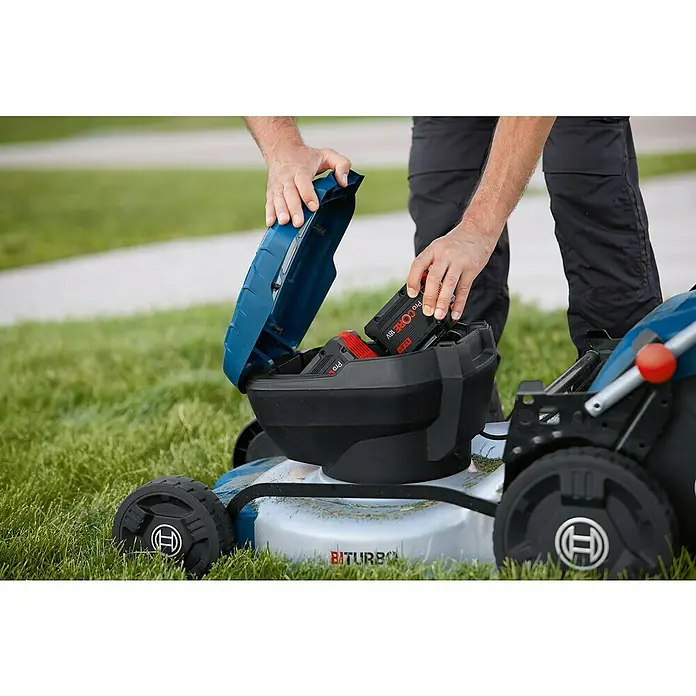 Bosch Professional AMPShare 18V Akku-Rasenmäher GRA 18V2-46 - 18 V, Ohne Akku, Schnittbreite: 46 cm - Ein Mann legt Bosch ProCore 18V-Akkus in einen Rasenmäher. Der Rasenmäher ist blau und hat schwarze Räder mit dem Bosch-Logo.
