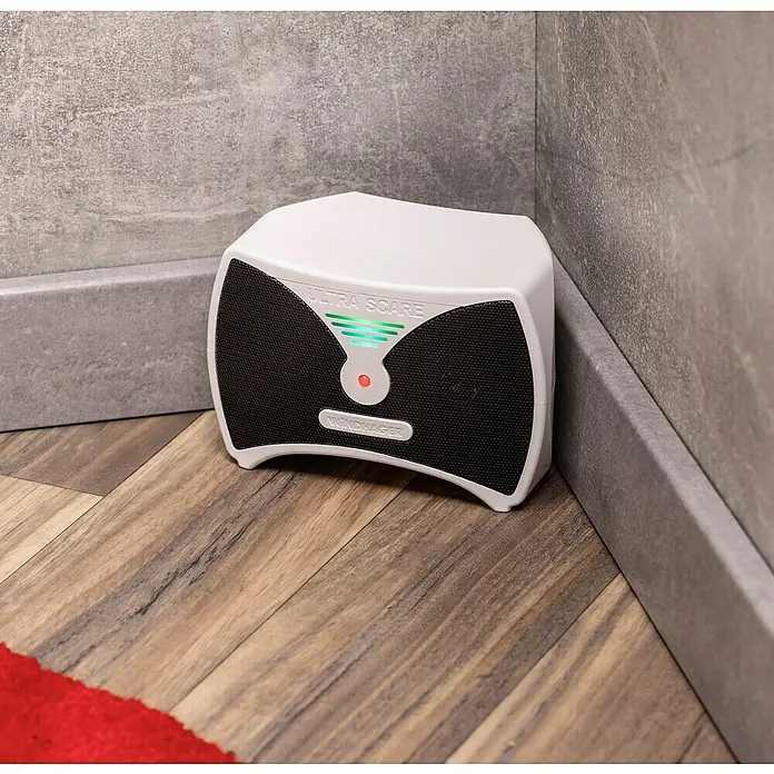 Windhager Ratten- & Mäusebekämpfung Ultra Care - Nager, Akkubetrieben - Ein weißer, elektronischer Schädlingsbekämpfer "Ultra Scare" steht in einer Ecke auf einem Holzboden.