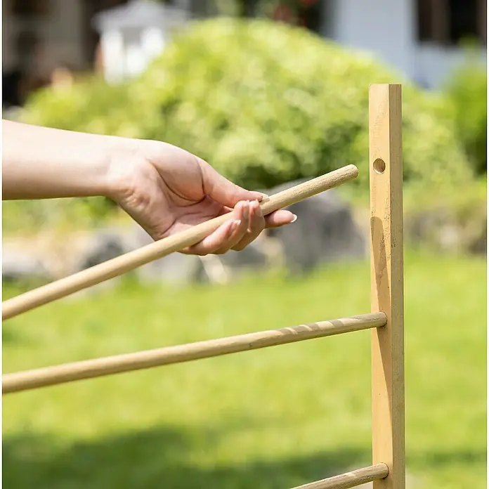 Windhager Rankhilfe - B x H: 60 x 120 cm, Holz - Eine Hand setzt eine Holzstange in einen hölzernen Wäscheständer im Freien ein. Praktisch für den Garten!