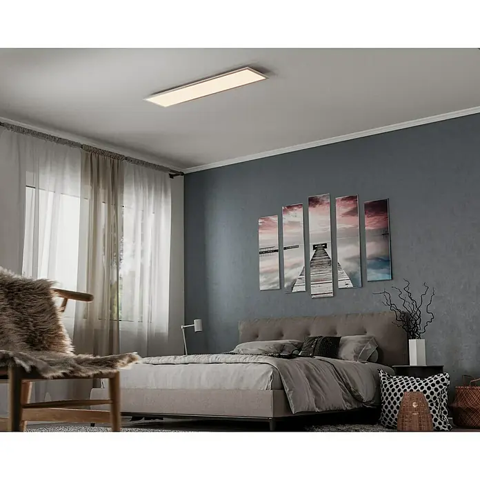 Ledvance LED-Panel Planon Plus - 36 W, 120 x 30 cm, Weiß, Warmweiß - Deckenleuchte in einem Schlafzimmer mit großem Bett, Stuhl und Kunstwerken. Die moderne Leuchte sorgt für eine angenehme Beleuchtung im Raum.