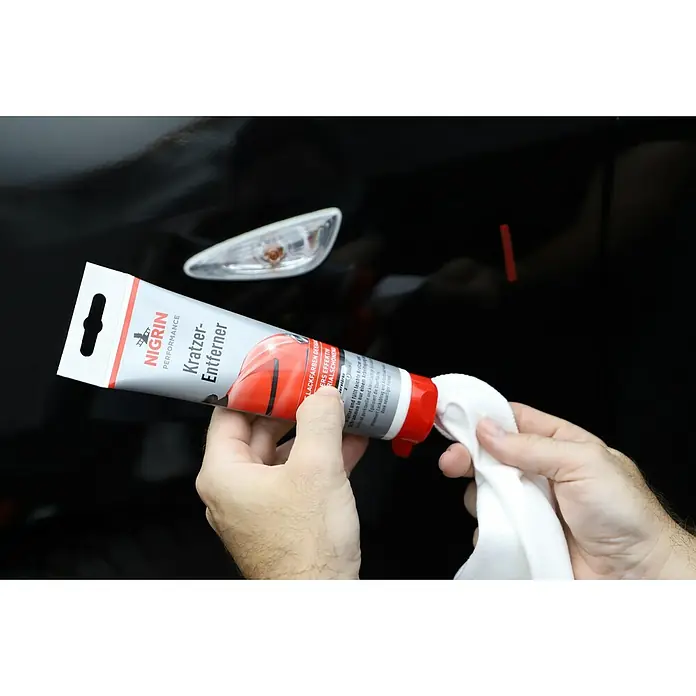 Nigrin Kratzer-Entferner - 150 g - Nigrin Performance Kratzer-Entferner wird auf ein Tuch gegeben, um Kratzer auf einem schwarzen Auto zu entfernen.