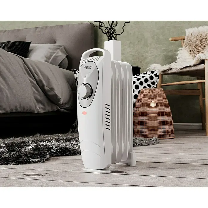 Voltomat HEATING Radiador de aceite Mini - 600 W, Habitaciones de hasta 6 m², Blanco - Toma de un radiador eléctrico sobre un piso de madera. El calentador es blanco y cuenta con un dial para el control de la temperatura.