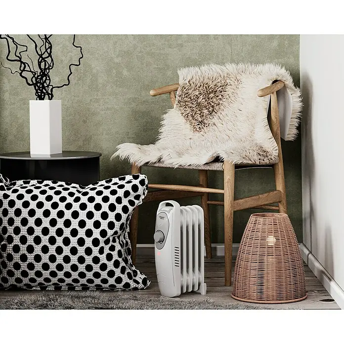 Voltomat HEATING Ölradiator Mini - 600 W, Raumgröße bis ca. 6 m², Weiß - Ein Detailaufnahme eines Raumes mit einem weißen Heizgerät, einem Stuhl mit Fell und einer gemusterten Kissen, die eine gemütliche Atmosphäre schaffen.