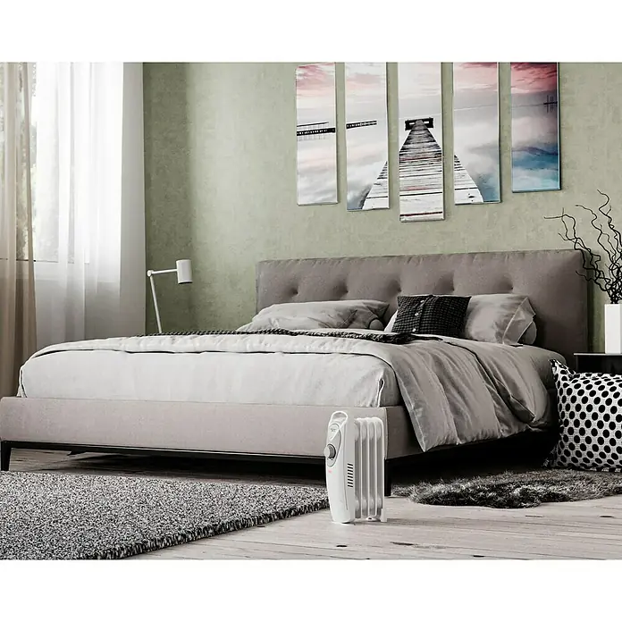 Voltomat HEATING Ölradiator Mini - 600 W, Raumgröße bis ca. 6 m², Weiß - Ein Heizkörper steht im Schlafzimmer, sorgt für Wärme. Das Zimmer ist mit einem Bett und Bildern dekoriert.