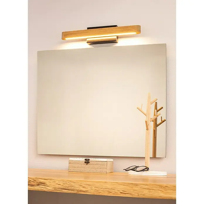 Britop Lighting Wandleuchte Forestier - 5,5 W, LED, L x B x H: 400 x 60 x 80 mm, Braun - Quadratischer Spiegel mit Holzleuchte darüber, auf einem rustikalen Holztisch mit Dekorationen.