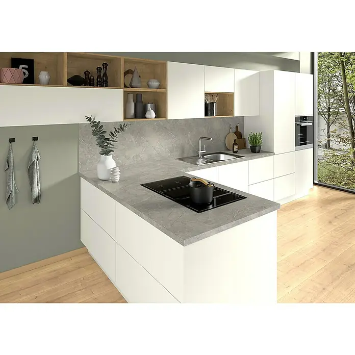 CUCINE Küchenarbeitsplatte nach Maß - Marmor hellgrau, Stärke: 3,8 cm, Breite: 63,5 cm - Eine moderne Küche mit weißen Schränken, grauer Arbeitsplatte und Kochinsel. Die offene Gestaltung und die natürliche Beleuchtung schaffen eine einladende Atmosphäre.
