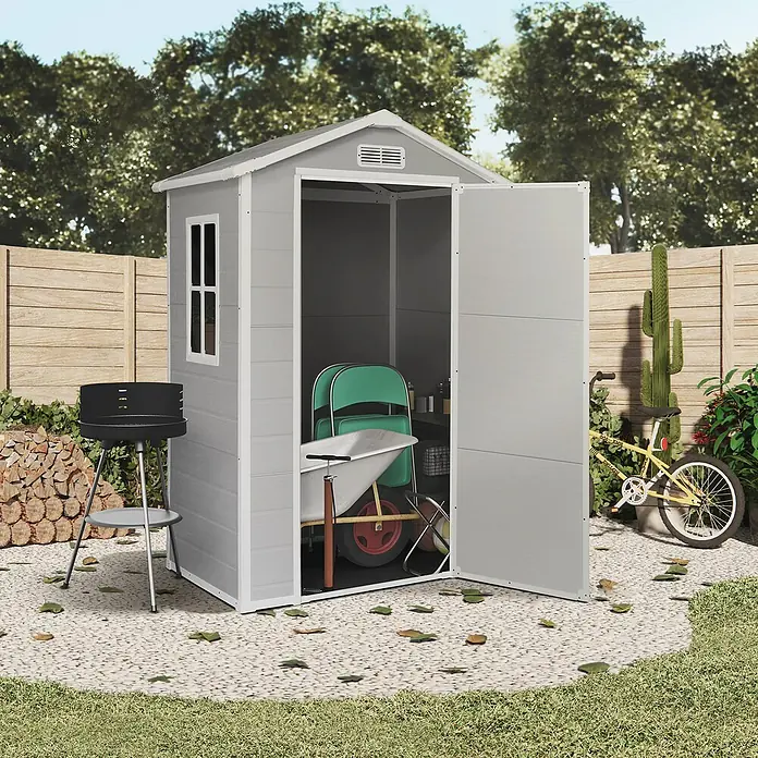 The Space Plus Gerätehaus One 1.36 - Außenmaß inkl. Dachüberstand (B x T): 134 x 103 cm, Kunststoff, Grundfläche: 1,37 m² - Eine graue Gartengerätehütte mit geöffneter Tür, in der sich Gartengeräte befinden, steht auf einem Kiesweg.