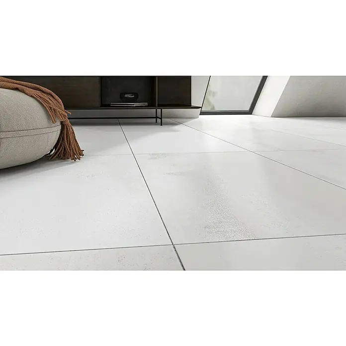 Oxyd Bodenfliese - 60 cm x 120 cm x 9 mm, Weiß, Schimmernd, Rektifiziert - Nahaufnahme eines Raumes mit weißen Fliesenböden, einem beigen Sitzsack mit Fransen und einem modernen TV-Möbel. Die Fliesen dominieren und strahlen Sauberkeit aus.