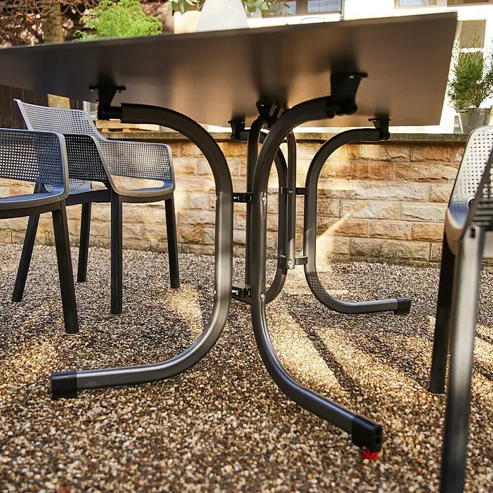 Siena Garden Urban Lights Gartenmöbel-Set District Sessel/Sola Tisch - 5 -tlg., Polypropylen, Olive/Anthrazit - Nahaufnahme eines schwarzen Gartentisches mit Stühlen auf einem Kiesweg, der die robuste Bauweise und das moderne Design des Tisches hervorhebt.