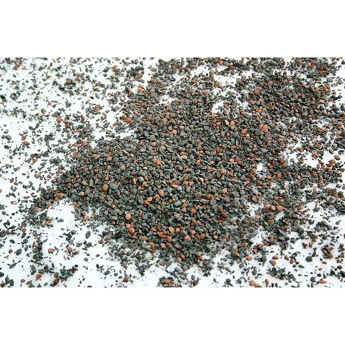 Winterstreu GripTon - 10 l, Sack - Streugut auf Schnee: Eine Nahaufnahme von kleinen, grauen und roten Steinchen, die auf einer weißen, verschneiten Oberfläche verstreut sind.