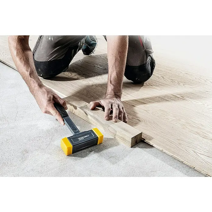 Halder Secural Schonhammer - Maße Kopf: 30 x 40 mm, Mittelhart - Ein Handwerker verlegt mit einem Gummihammer Laminatboden. Der Hammer ist grau mit gelben Einsätzen und wird zum Einklopfen der Dielen genutzt.