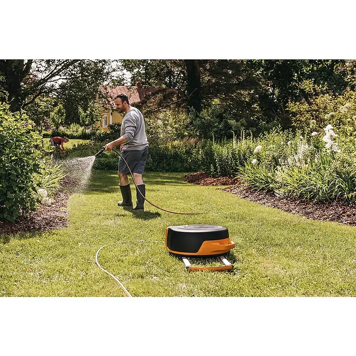 Fiskars X-series Automatische Schlauchtrommel XL mit Rädern - Schlauchlänge: 25 m - Ein Mann bewässert seinen Garten mit einem Schlauch von einer Fiskars Schlauchtrommel.