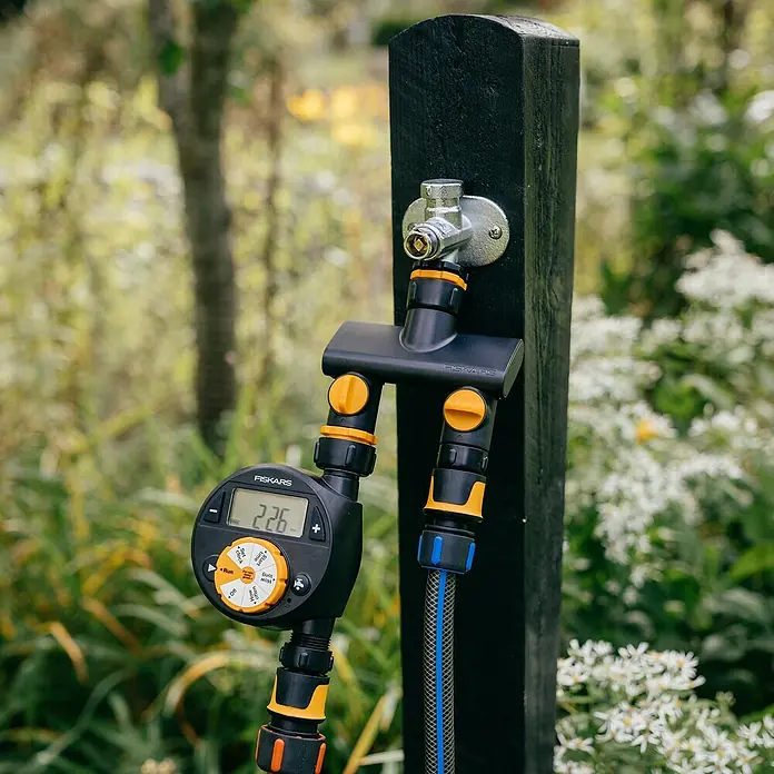 Fiskars 2-Wege-Ventil - Ø 21 mm (G 1/2"), Ø 26,5 mm (G 3/4") und Ø 33,3 mm (G 1") - Der Fiskars Wasserverteiler mit Zeitschaltuhr, ein praktisches Gerät für die Gartenbewässerung. Zu sehen sind auch die gelben und schwarzen Akzente des Produkts.