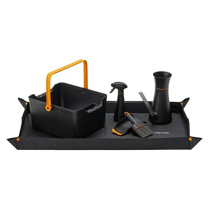 Fiskars Kehrschaufel-Set - Kunststoff - Das Bild zeigt ein Fiskars-Gartenset mit einer Schaufel, einer Sprühflasche und einer Gießkanne auf einer schwarzen Matte. Der Tragekorb ist mit einem gelben Griff versehen.