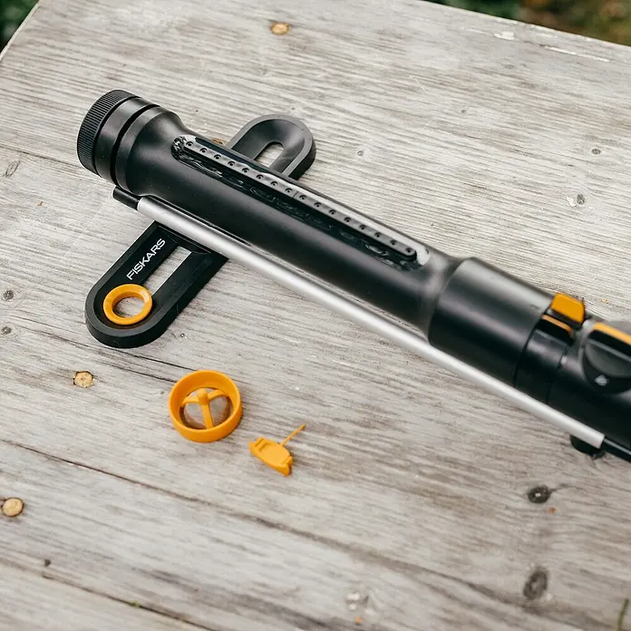 Fiskars Ersatzteil-Set Oszillierende Regner - Passend für: Fiskars X-Series™ Oszillierende Regnern S–L und S–M sowie Comfort Oszillierende Regnern S–L und S–M - Nahaufnahme eines Fiskars-Rasensprengers mit Zubehör auf einer Holzoberfläche.