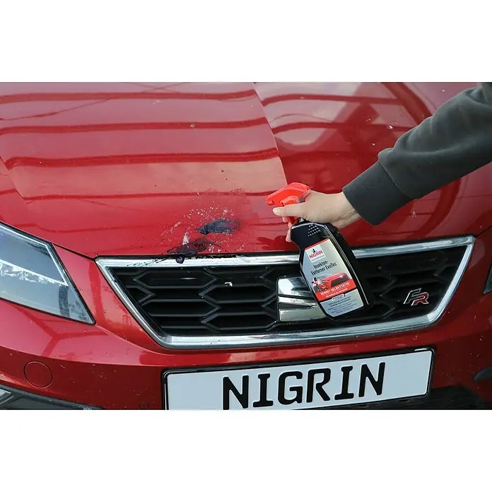 Nigrin Performance Insektenentferner mit Indikator - 500 ml - Aufnahme eines roten Autos, auf das Nigrin Insekten-Entferner EvoTec aufgesprüht wird, um Insekten zu entfernen.