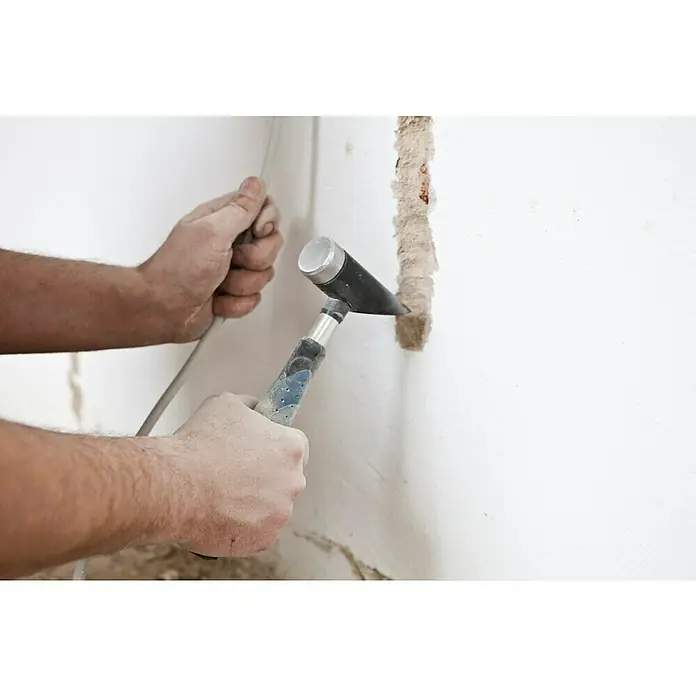 Picard Meißelhammer Meißelmeister - Gewicht Kopf: 600 g, Spezialstahl - Ein Bauarbeiter stemmt mit einem Meißel und Hammer eine Furche in eine weiße Wand, um Kabel zu verlegen. Staub bedeckt Hände und Werkzeug.