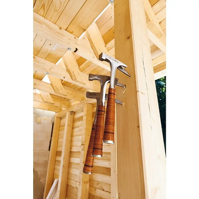 Picard Latthammer - Gewicht Kopf: 800 g, Material Griff: Leder - Drei Zimmermannshämmer mit Holzgriff hängen an einem Holzpfosten in einem Holzrahmengebäude.