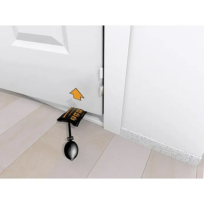 Montagekissen Winbag Mini - Traglast: 70 kg - Hier ist eine Nahaufnahme eines WINBAG-Werkzeugs, das zwischen einer Tür und dem Rahmen platziert ist, mit einem gelben Pfeil, der darauf zeigt.