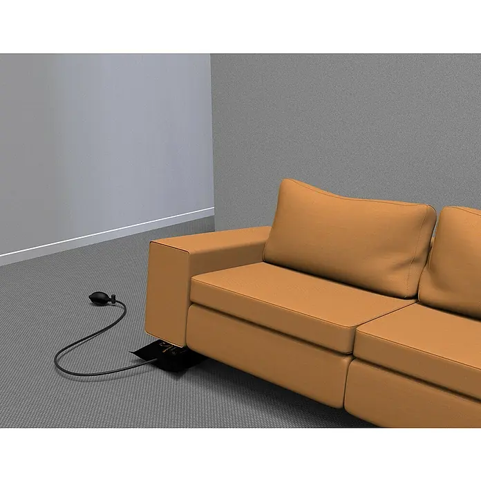 Montagekissen Winbag Max - Traglast: 250 kg - Das Bild zeigt ein Möbel-Lifter-Werkzeug unter einem orangefarbenen Sofa in einem Raum mit grauen Wänden und einem grauen Teppichboden.