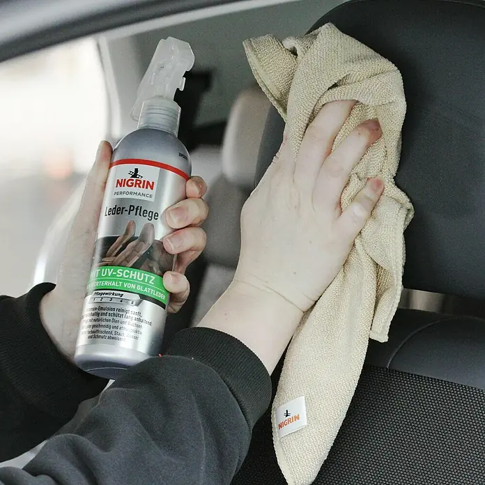 Nigrin Performance Lederpflege - 300 ml - Jemand reinigt einen Autositz mit Nigrin Lederpflege und einem Tuch.