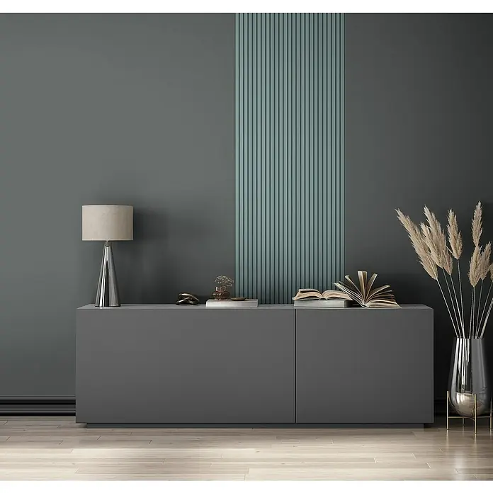 Marburg GZSZ Vliestapete - Schwarz, Uni, 10,05 x 0,53 m - Ein graues Sideboard mit Dekorationen, einer Lampe und Trockenblumen vor einer dunkelgrünen Wand mit vertikalen Akzenten.