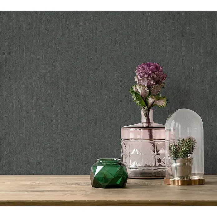 Marburg GZSZ Vliestapete - Schwarz, Uni, 10,05 x 0,53 m - Stillleben mit rosafarbener Vase, grüner Schale und Glasglocke mit Kaktus auf einem Holztisch vor grauem Hintergrund.