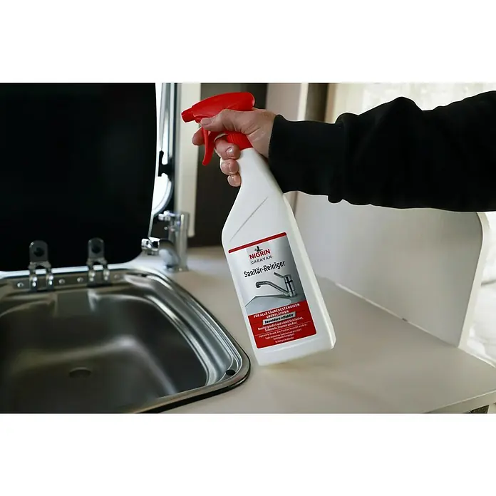 Nigrin Caravan Sanitärreiniger - 750 ml - Nigrin Caravan Sanitär-Reiniger wird über einem Waschbecken in einem Wohnmobil gezeigt. Reinigungsmittel für alle säurebeständigen Oberflächen.