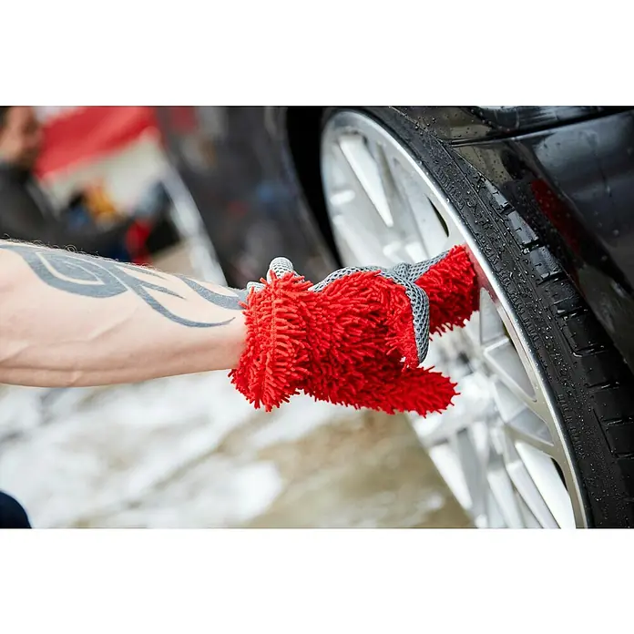 Nigrin Performance Finger- & Waschhandschuh - Rot, Mikrofaser - Das Bild zeigt eine Hand mit einem roten Waschhandschuh, die einen Reifen reinigt. Der Handschuh ist ideal für die Autowäsche.