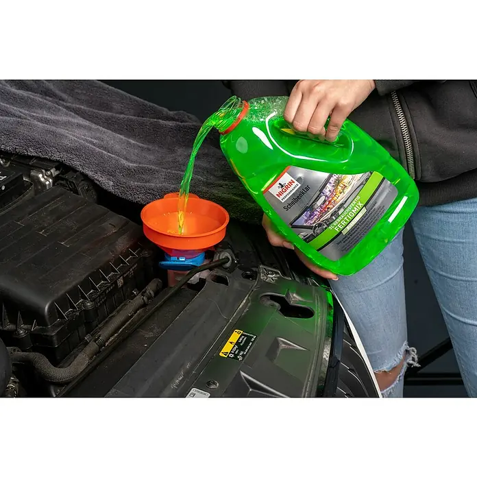 Nigrin Performance Scheibenklar Fertigmix - 3 l, Duft: Bubblegum - Eine Person füllt Scheibenreiniger von Nigrin Performance in den Behälter eines Autos. Der grüne Reiniger fließt durch einen Trichter.