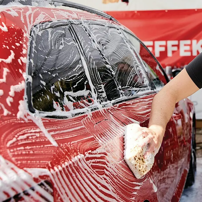 Nigrin Performance Auto-Shampoo Snowfoam - 1 l - Rotes Auto wird mit einem Schwamm und Seife gewaschen, um es sauber und glänzend zu halten. Perfekt für die Autopflege.