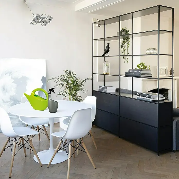 Scheurich Smilla Handsprüher - 0,7, Matt Anthracite - Einladendes Interieur mit einem weißen Esstisch, umgeben von Stühlen, mit einer grünen Gießkanne und einer grauen Sprühflasche als Blickfang.