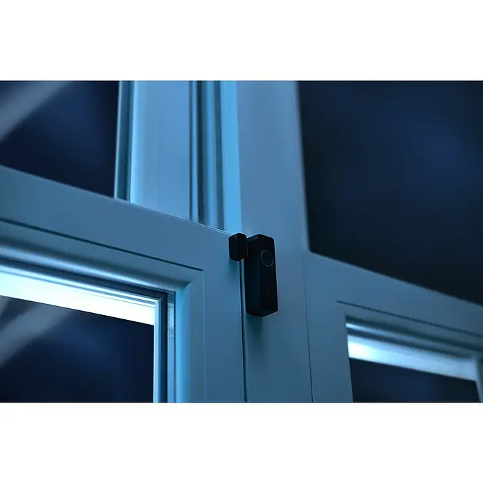Philips Hue Sensor de ventana y puerta - Negro, ZigBee, 2 unidades - Primer plano de un sensor de puerta y ventana Ring Alarm conectado a un marco de ventana blanco, brindando seguridad para el hogar.