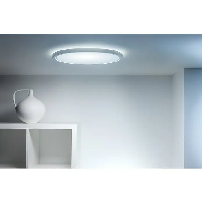 Philips Wiz Smart-LED-Deckenleuchte rund Tunable White & Color SuperSlim - 22 W, Ø x H: 43 x 4,8 cm, Weiß, RGBW - Minimalistisches Interieur mit einer modernen Deckenleuchte, die helles, gleichmäßiges Licht spendet. Eine weiße Vase auf einem Regal ergänzt das schlichte Design.