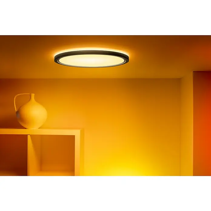Philips Wiz Smart-LED-Deckenleuchte rund Tunable White & Color SuperSlim - 32 W, Ø x H: 55 x 4,8 cm, Schwarz, RGBW - Elegante Deckenleuchte in einem warmen Raum. Die runde Lampe mit dunklem Rand spendet sanftes Licht und schafft eine behagliche Atmosphäre.
