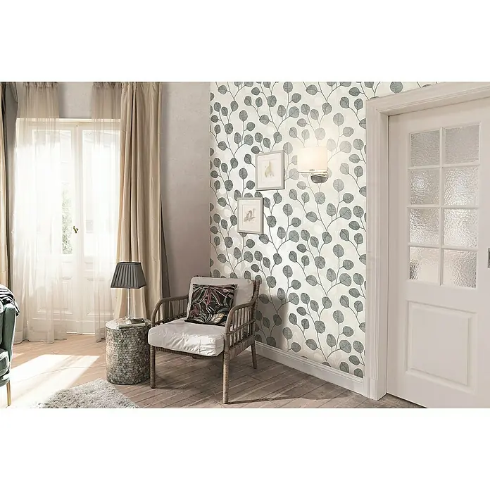 Marburg GZSZ Papel pintado de vinilo - Gris, Floral, 10 x 0,53 m - Un interior acogedor con un sillón de ratán, una lámpara de mesa sobre una mesa auxiliar y un papel pintado floral que crea un ambiente agradable.