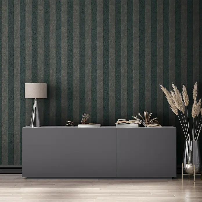 Marburg GZSZ Vliestapete - Schwarz, Streifen, 10,05 x 0,53 m - Ein graues Sideboard mit Deko-Elementen wie Lampe, Buch und Vase mit Ziergras vor einer gestreiften Tapete.