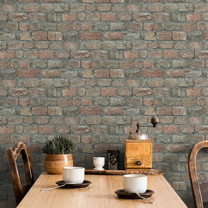 Marburg GZSZ Vliestapete Steinwand - Terra, Steinoptik, 10,05 x 0,53 m - Aufnahme eines Tisches mit Kaffeetassen, einer Pflanze und einer Kaffeemühle vor einer Ziegelwand. Dekorative und gemütliche Atmosphäre.