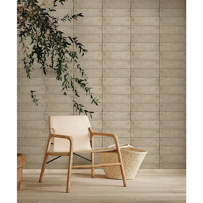 Marburg GZSZ Vliestapete - Beige, Betonoptik, 10,05 x 0,53 m - Einladender Raum mit beigem Ledersessel und Weidenkorb vor einer Wand mit beigefarbenen Fliesen.