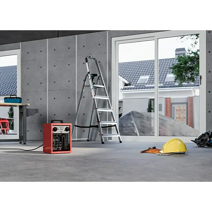 Voltomat HEATING Bauheizer - Passend für: Raumgröße bis ca. 20 m², 1.000 W - 2.000 W, Nennspannung: 220 V - 240 V, Rot, IP24 - Werkstatt-Szene mit einem roten Heizlüfter, einer Leiter mit Bohrmaschine, Werkzeug, Schutzhelm und einer Werkbank vor Betonwänden.