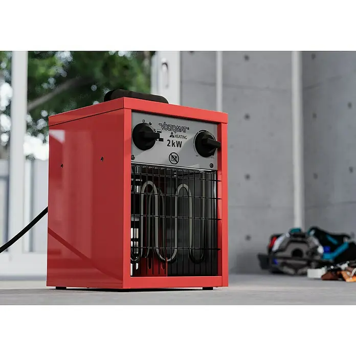 Voltomat HEATING Bauheizer - Passend für: Raumgröße bis ca. 20 m², 1.000 W - 2.000 W, Nennspannung: 220 V - 240 V, Rot, IP24 - Roter Voltomat Heizlüfter mit schwarzem Kabel, der auf einer grauen Oberfläche steht und ein Gitter vor den Heizstäben hat.