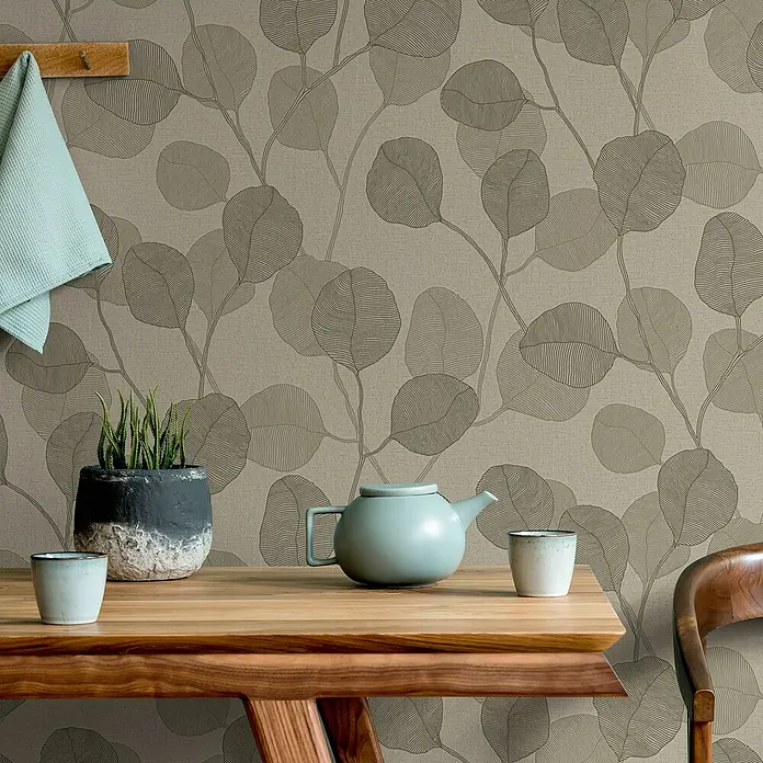 Marburg GZSZ Vliestapete Blätterranke - Beige/Braun, Floral, 10,05 x 0,53 m - Elegantes Stillleben mit einer hellblauen Teekanne, Tassen und einer Pflanze auf einem Holztisch, vor einer floral gemusterten Tapete.