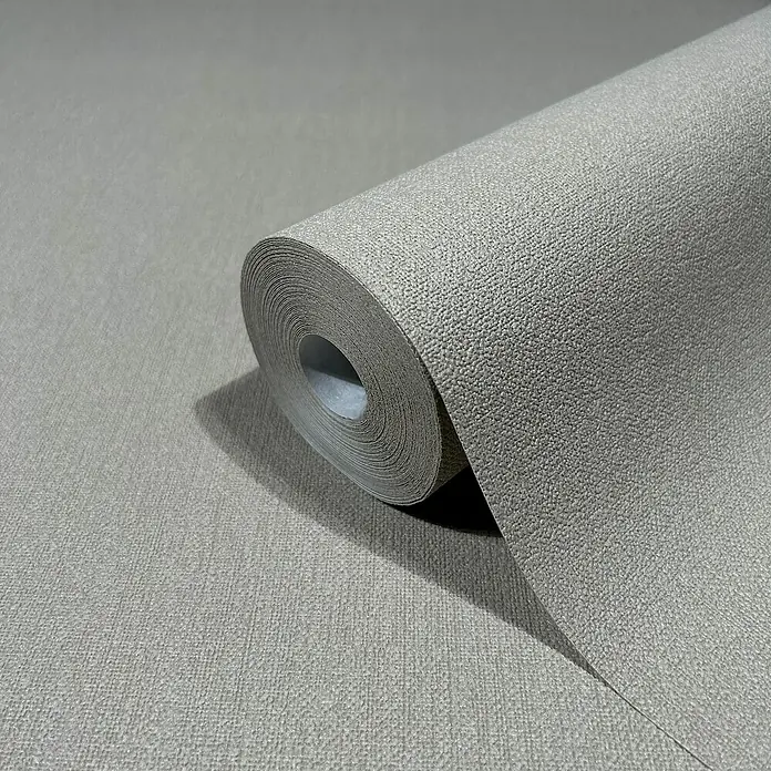 Marburg GZSZ Vliestapete - Mittelgrau, Uni, 10,05 x 0,53 m - Nahaufnahme einer Rolle grauer Textiltapete, die sich teilweise abrollt und die feine Textur des Materials zeigt.