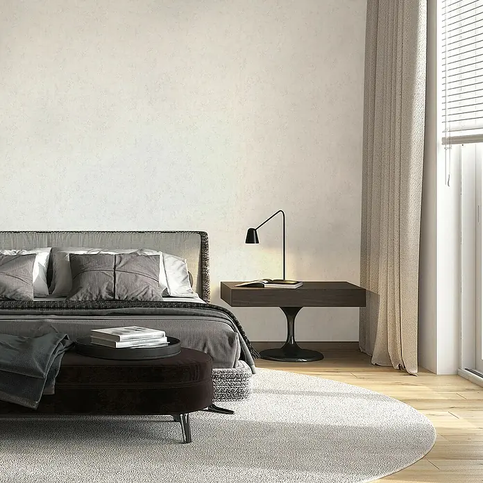 Marburg GZSZ Vliestapete - Shadow-Cremebeige, Uni, 10,05 x 0,53 m - Ein Schlafzimmer mit einem gepolsterten Bett, einem Nachttisch mit Lampe und einem runden Teppich.