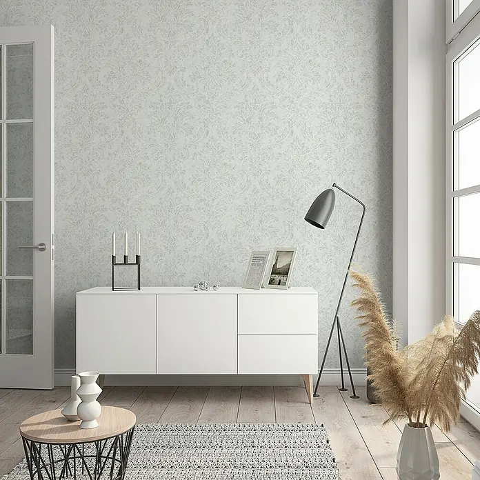 Marburg GZSZ Vliestapete - Weiß/Beige, Ornament, 10,05 x 0,53 m - Ein stilvolles Interieur mit einer weißen Kommode, einer eleganten Stehlampe und dekorativen Vasen.