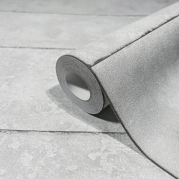 Marburg GZSZ Vliestapete - Grau, Betonoptik, 10,05 x 0,53 m - Nahaufnahme einer grauen Tapetenrolle mit Ziegelmuster. Sie ist auf einer horizontalen, strukturierten Fläche platziert.
