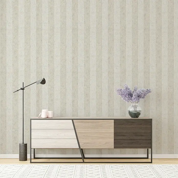 Marburg GZSZ Vliestapete - Beige, Streifen, 10,05 x 0,53 m - Schrank mit Schubladen und Ablageflächen, kombiniert mit einer Stehlampe und einem Blumenarrangement, vor einem gestreiften Hintergrund.